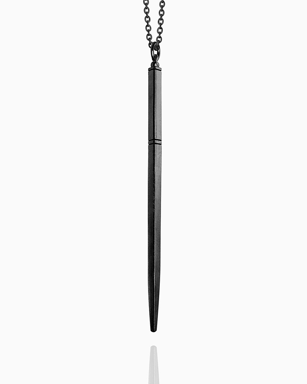 A blackened wand necklace made of sterling silver hanging against a white background. This wand has a tapered square shape and is completely smooth except for three carved horizontal lines to define the wand handle.
