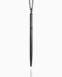 A blackened wand necklace made of sterling silver hanging against a white background. This wand has a tapered square shape and is completely smooth except for three carved horizontal lines to define the wand handle.