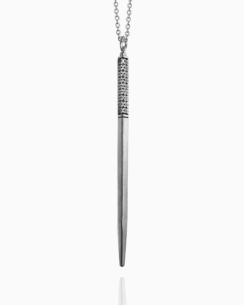 A sterling silver wand necklace hanging against a white background. This minimal wand has three engraved lines to define the handle—one at the top and two at the bottom. In between the lines, there is a floral pattern hand engraved into all four sides of the wand.
