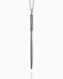 A sterling silver wand necklace hanging against a white background. This minimal wand has three engraved lines to define the handle—one at the top and two at the bottom. In between the lines, there is a floral pattern hand engraved into all four sides of the wand.