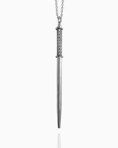A polished sterling silver wand pendant hangs from a chain against a white background. The square shape has two silver rings around it—one at the top and another one-third of the way down the wand to define the handle. Between those rings, the handle of the wand is hand-engraved with a floral pattern on all four sides.