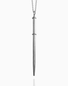 A square wand pendant made of sterling silver hanging from a chain against a white background. A silver ring around the top and another silver ring one-third of the way down the wand define the handle on this polished necklace.